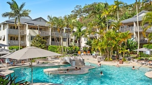 Un complexe hôtelier doté d’une piscine, de chaises longues et de palmiers.
