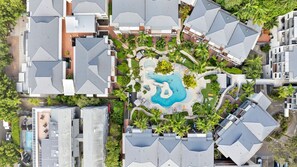 An aerial view of a residential area with modern houses, a central swimming pool, and surrounding greenery. - French Quarter 322 Beautiful One Bedroom Apartment (Noosa Heads)