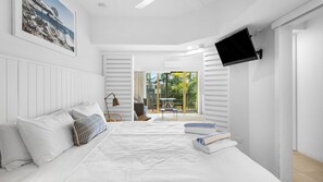 A bedroom with a bed, a TV mounted on the wall, and a view of the outdoors. - French Quarter 322 Beautiful One Bedroom Apartment (Noosa Heads)