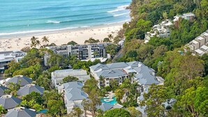 Una zona residenziale costiera con spiaggia, vegetazione lussureggiante e edifici moderni.