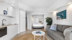 A modern apartment with a kitchen, a living area with a sofa, and a bedroom with a bed. - French Quarter 322 Beautiful One Bedroom Apartment (Noosa Heads)