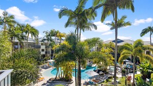 Un resort con piscina circondata da palme e lettini.