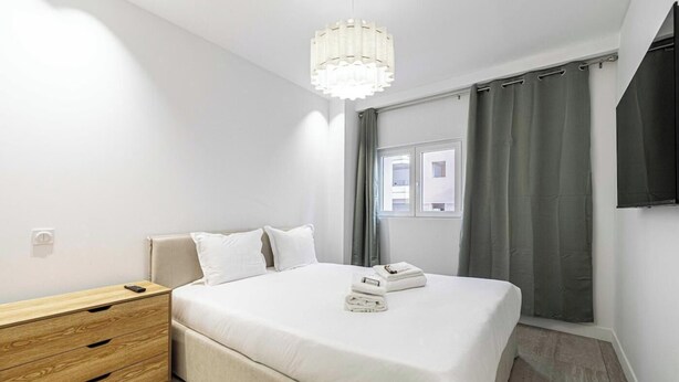 Una camera da letto con un letto, un comodino e una lampada a sospensione.