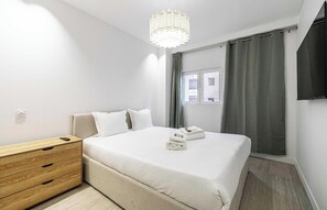 Un dormitorio con cama, mesita de noche y lámpara colgante.