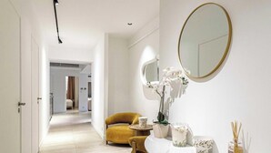 Un bagno moderno con uno specchio rotondo, una sedia gialla e un vaso con fiori bianchi.