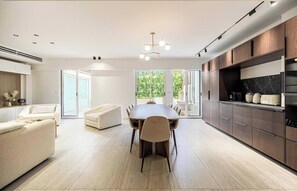 A modern kitchen with a dining area, large windows, and a view of greenery. - JUST A 5-MINUTE WALK FROM THE BEACH AND THE FAMOUS BOULEVARD DE LA CROISETTE (Cannes)