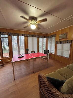 A room with a ping pong table, a ceiling fan, and large windows with blinds. - Bring the whole family to this large Simpsonville home that sleeps 10 people. (Simpsonville)