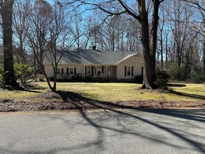 A residential house with a front porch, a lawn, and trees in the background. - Bring the whole family to this large Simpsonville home that sleeps 10 people. (Simpsonville)
