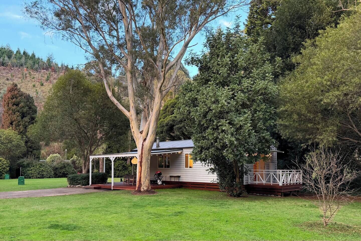 A house with a covered porch, surrounded by a well-maintained lawn and various trees.