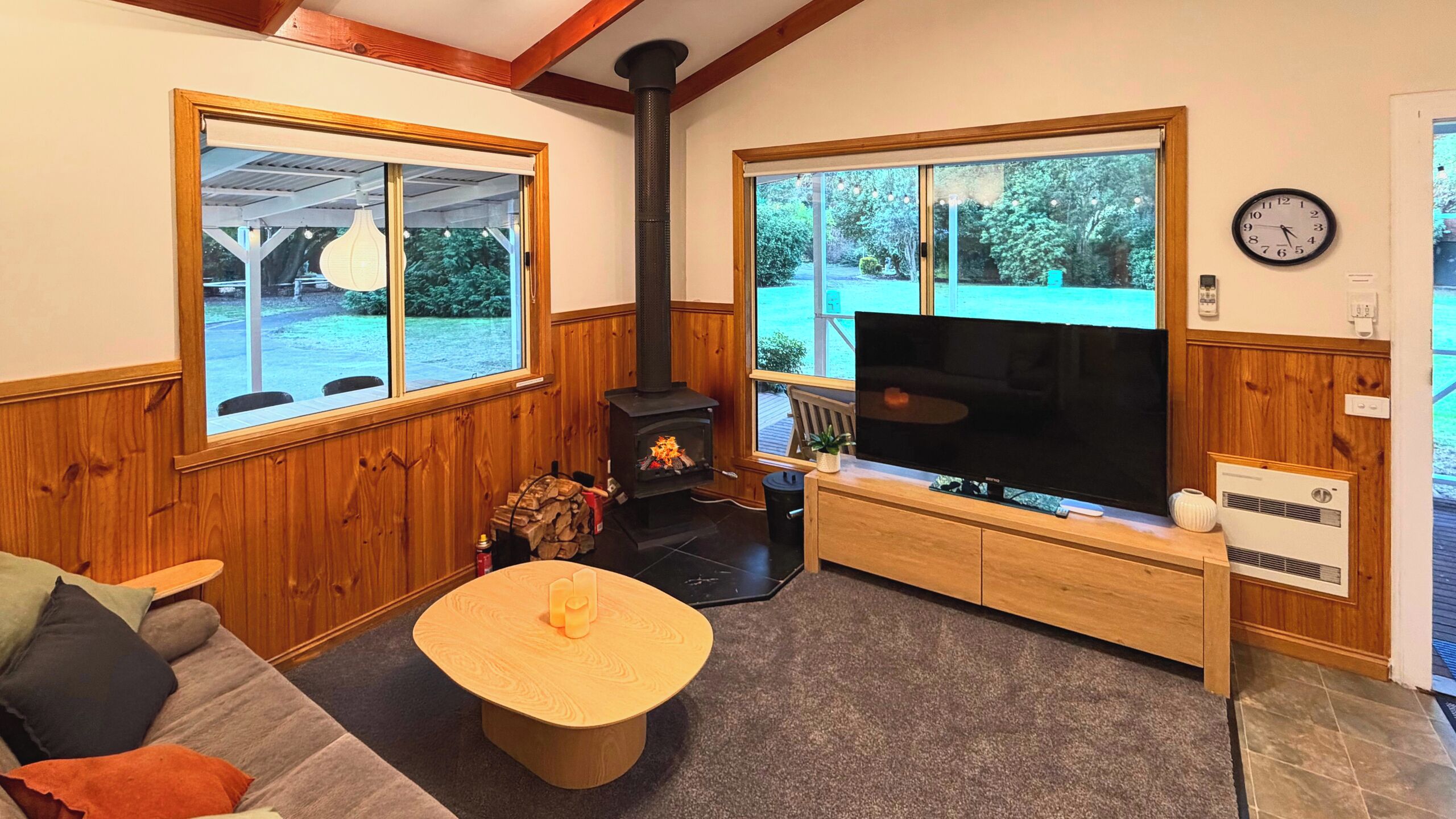 Ein gemütliches Wohnzimmer mit Kamin, Fernseher und großen Fenstern.
