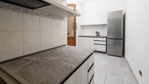 Una cocina con encimera de mármol, refrigerador de acero inoxidable y puerta de madera.