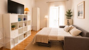 Ein Schlafzimmer mit einem Bett, einem Fernseher, einem Kleiderschrank und einem Fenster mit Vorhängen.