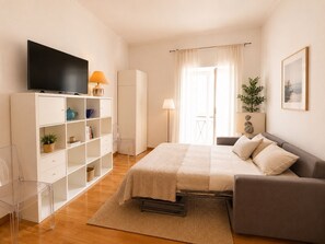 Ein Schlafzimmer mit einem Bett, einem Fernseher, einem Kleiderschrank und einem Fenster mit Vorhängen.