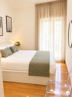 Ein Schlafzimmer mit einem Bett, einem Nachttisch mit Lampe, einer Topfpflanze und einem Fenster mit Vorhängen.