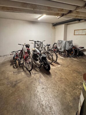 A parking garage with bicycles and a motorcycle.