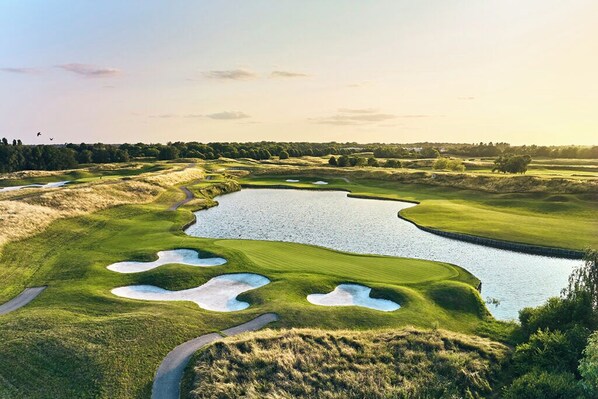 Un parcours de golf avec des bunkers, des obstacles d’eau et un ciel dégagé.