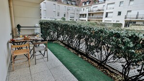 A balcony with a table set for two, a chair, and a small potted plant. - L’Élégant Cocon • Terrasse • Versailles • Paris • Gare SQY (Montigny-le-Bretonneux)