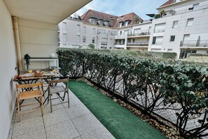 A balcony with a table set for two, a chair, and a small potted plant. - L’Élégant Cocon • Terrasse • Versailles • Paris • Gare SQY (Montigny-le-Bretonneux)
