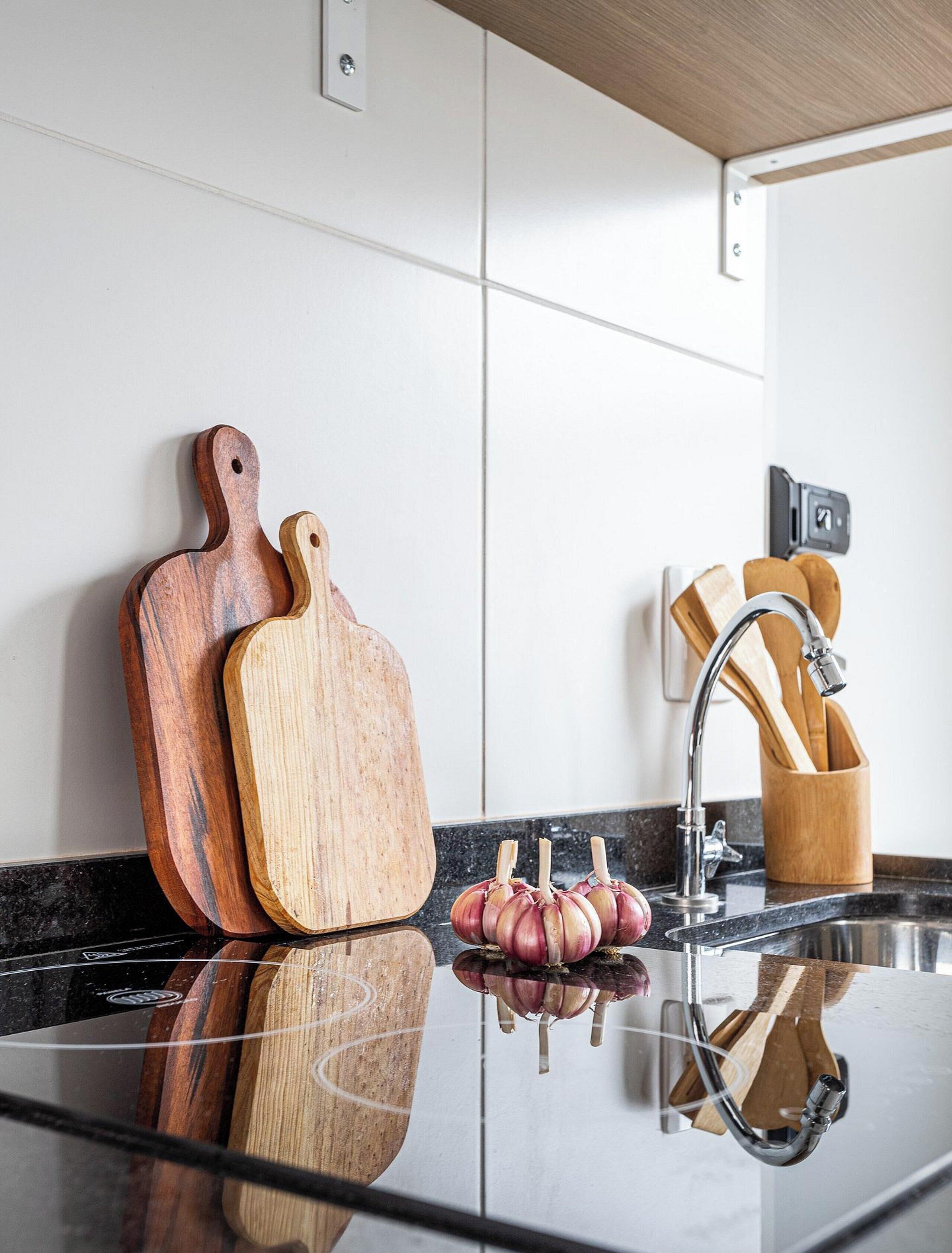Una cocina con tablas de cortar de madera, un lavamanos y un portalapices.