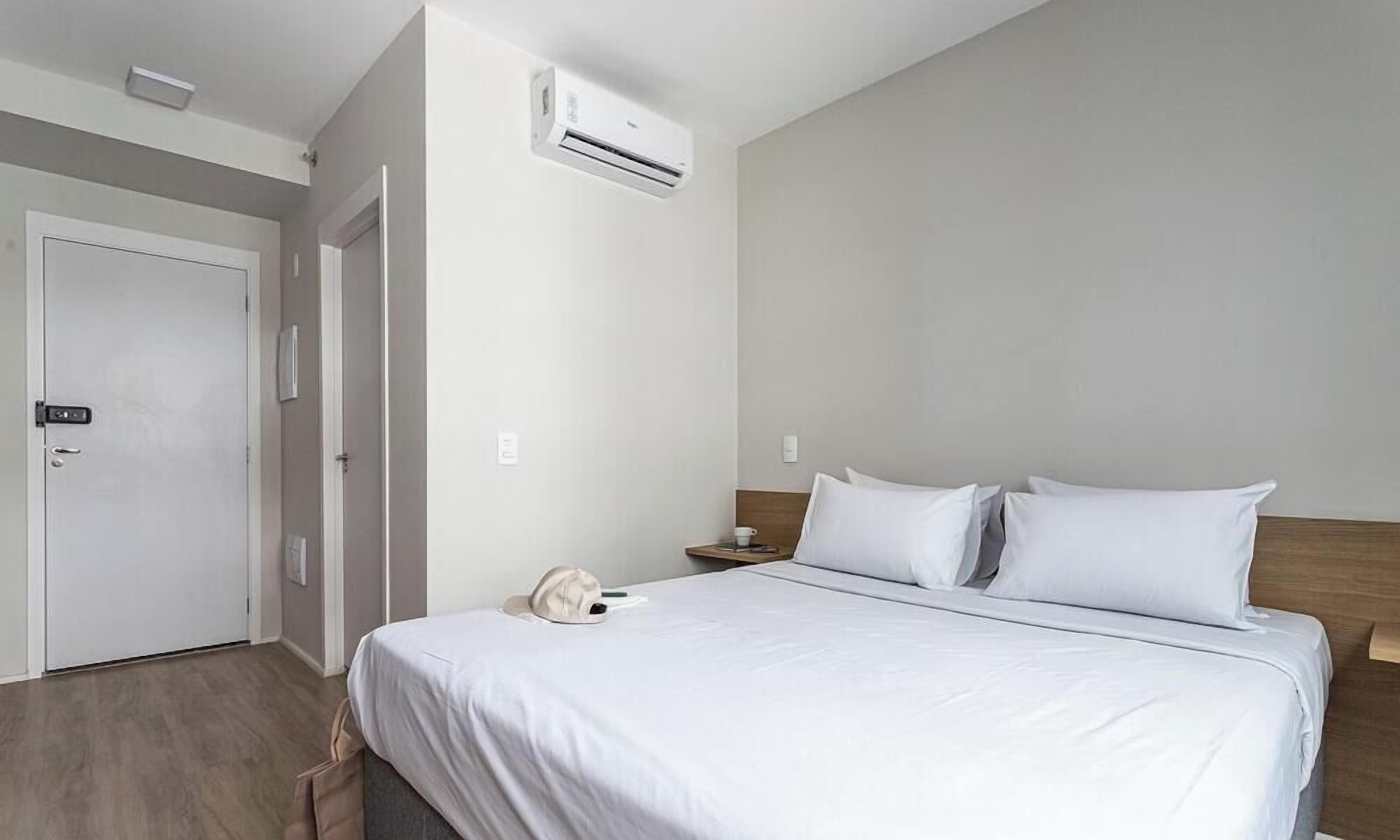 Ein Hotelzimmer mit Bett, Nachttisch und Klimaanlage.