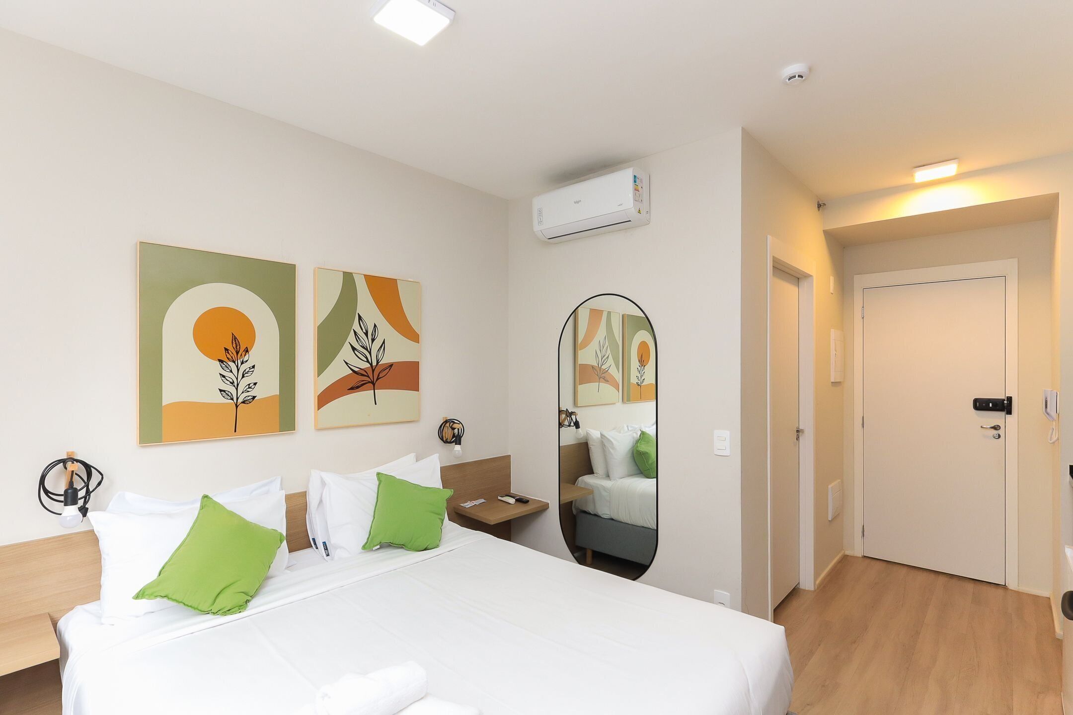 Een hotelkamer met een bed, nachtkastje, spiegel en kunst aan de muur.