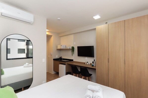 Una habitación de hotel con cama, escritorio con silla, televisión y armario.