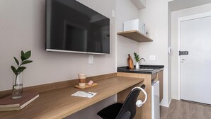 Une cuisine moderne avec un plan de travail en bois, une chaise noire, un réfrigérateur blanc et un grand téléviseur à écran plat fixé au mur.