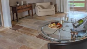 Een moderne woonkamer met een glazen tafel, een bank en een televisie aan de muur.