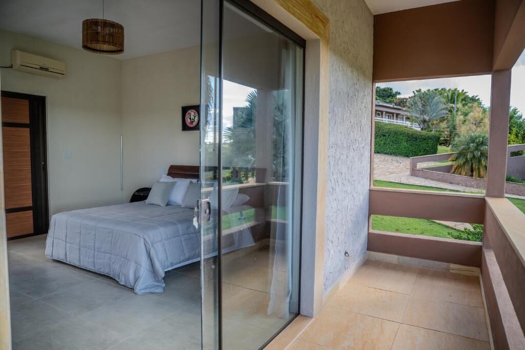 A bedroom with a bed, a sliding glass door leading to a balcony, and a view of the outdoors.