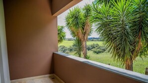 Een balkon met uitzicht op een groen landschap en palmbomen.