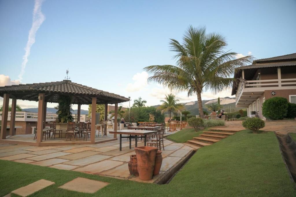 A patio area with a pergola, outdoor seating, palm trees, and a view of the mountains.