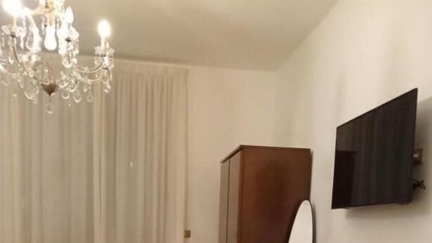 Un dormitorio con una cama, un escritorio de madera, un espejo y un televisor en la pared.