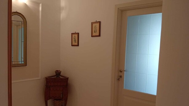 A hallway with a door, a mirror, and two framed pictures on the wall.