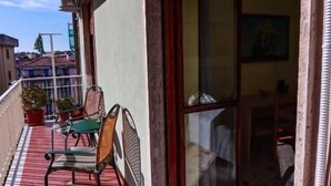 A balcony with a red tiled floor, a sliding glass door, and outdoor furniture including a chair and a table.