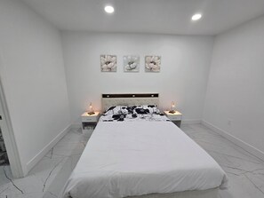 Ein Schlafzimmer mit einem Bett, zwei Nachttischen, einer Wandleuchte und drei Wandbildern.