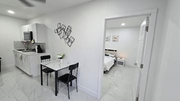 Un espace de vie compact comprenant un coin repas, une kitchenette et une chambre.
