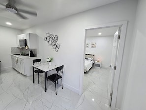 A compact living space with a dining area, kitchenette, and a bedroom.