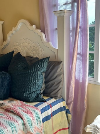 A bed with a decorative headboard, multiple pillows, and a colorful striped blanket.