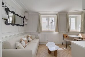 Ein modernes Wohnzimmer mit Sofa, Couchtisch, Esstisch und Stuhl.