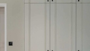 Une pièce avec une armoire blanche, une porte et un interrupteur sur le mur.