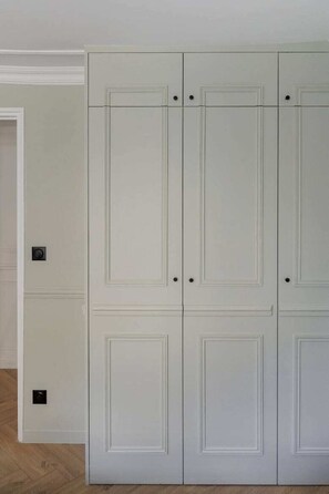 Ein Zimmer mit einem weißen Wandschrank, einer Tür und einem Lichtschalter an der Wand.