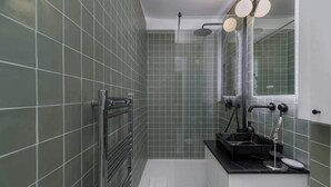 Une salle de bain avec une douche, un lavabo et un miroir.