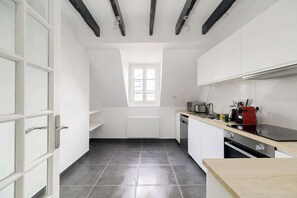 A compact kitchen with a window, a dishwasher, a red stove, and a wooden countertop. - Charming Flat near Madeleine (Paris)
