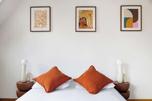 A bedroom with a bed, two pillows, and three framed artworks on the wall. - Charming Flat near Madeleine (Paris)