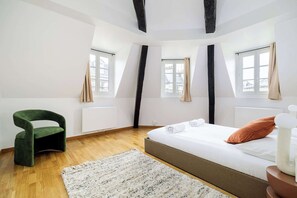 A bedroom with a bed, a chair, a window, and a radiator. - Charming Flat near Madeleine (Paris)