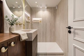 Ein modernes Badezimmer mit einem Holzwaschtisch, einem Spiegel, einem Handtuchhalter und einer Duschkabine.