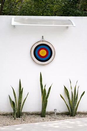Eine Wand mit Zielscheibe, drei Blumentöpfen und einer Leuchte.