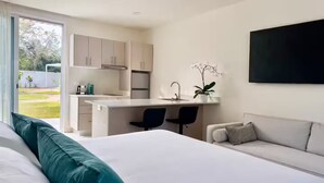 Una habitación de hotel moderna con cama, sofá, escritorio y kitchenette.