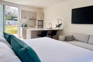 Ein modernes Hotelzimmer mit Bett, einer Couch, einem Schreibtisch und einer Küchenzeile.