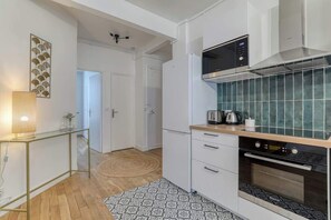 Eine moderne Küche mit weißen Schränken, einer Mikrowelle, einem Backofen und einer Kaffeemaschine.